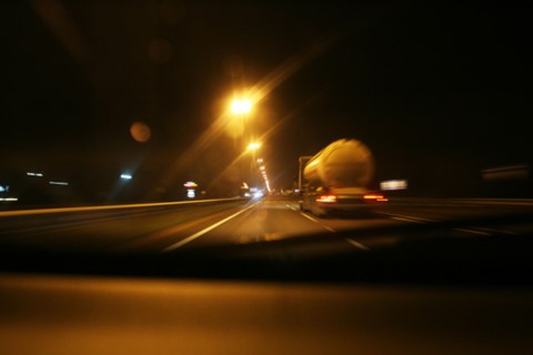 View out of a car at night with glaring streetlights and a blurry truck